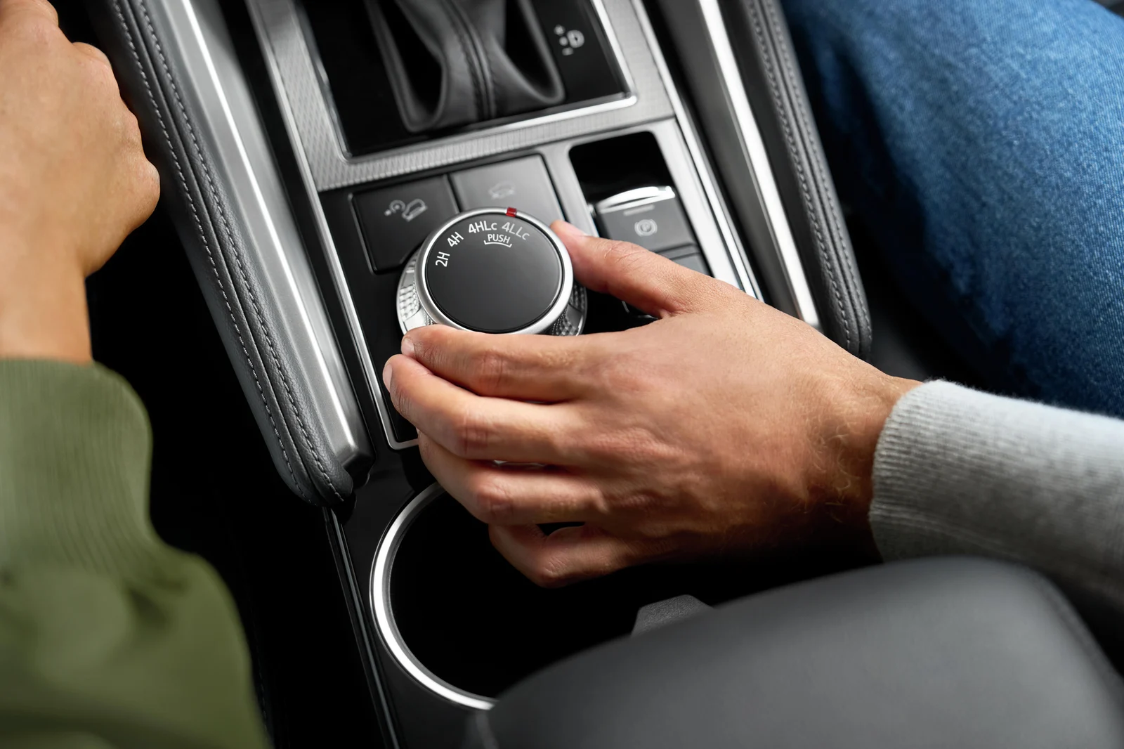 A driver’s hand turning the Mitsubishi Super Select 4WD dial, marked 2H, 4H, 4HLc and 4LLc
