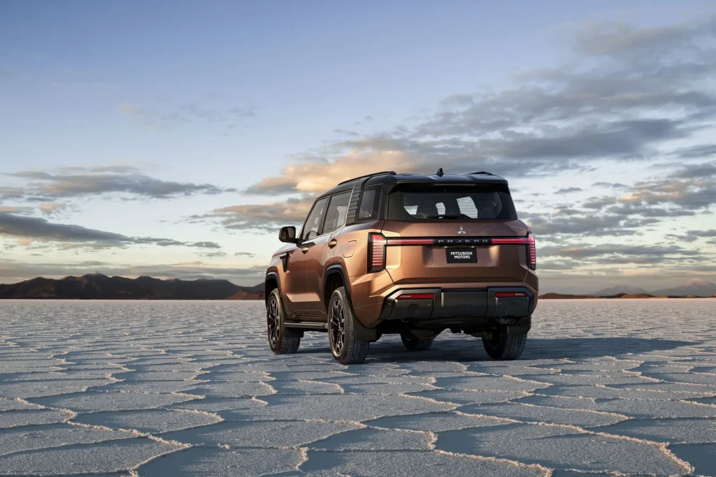 New Mitsubishi Pajero photographed from the rear on a salt pan at sunset, showing the full-width tail light bar