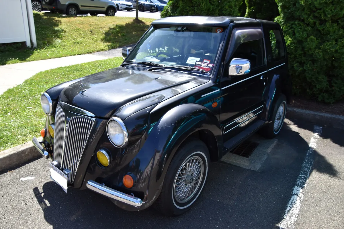 Dark blue Mitsubishi Pajero Junior Flying Pug with its retro upright grille and wire wheels