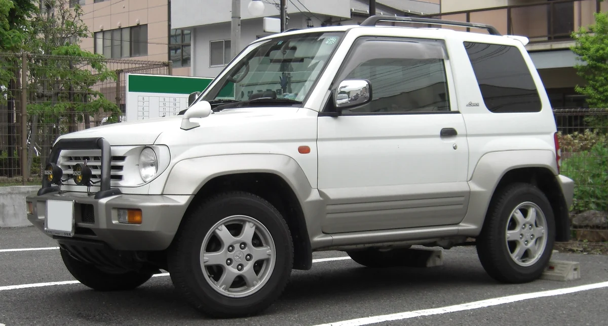 Silver and white Mitsubishi Pajero Junior with a front bull bar and wide wheel-arch flares